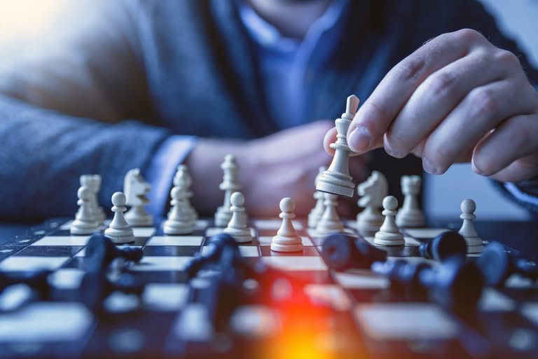 Hand moving a white king piece on a chessboard.