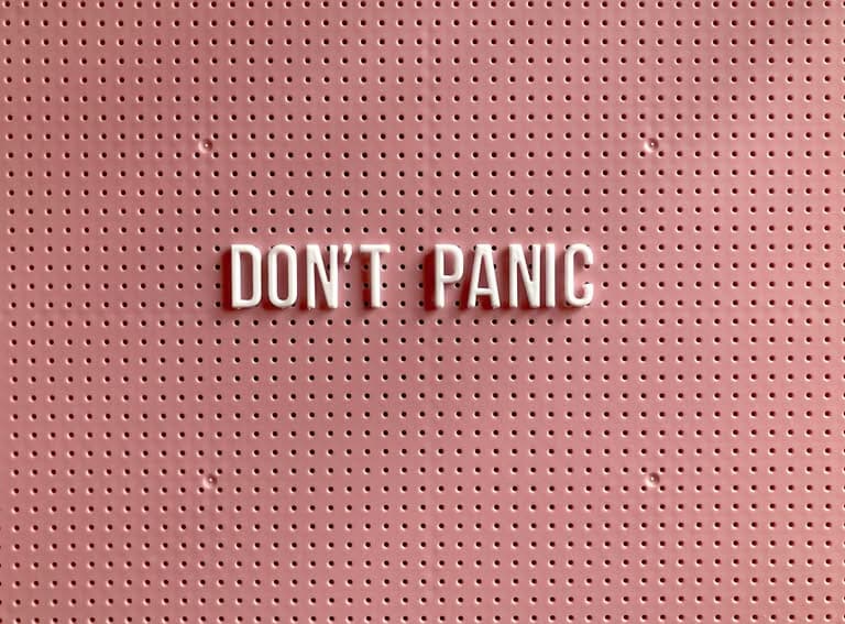 Pink pegboard with white letters spelling 'DON'T PANIC'.