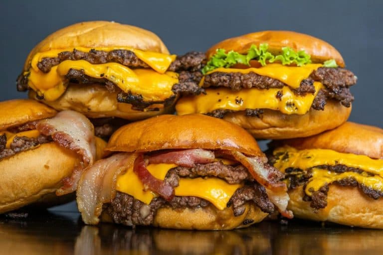 Five double cheeseburgers with melted cheese, bacon and lettuce.
