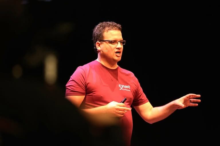 Speaker in maroon Yoast t-shirt presenting on stage.