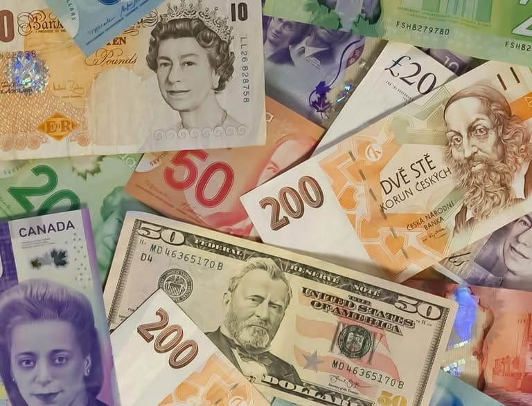A collection of diverse international banknotes including Pounds and Dollars.
