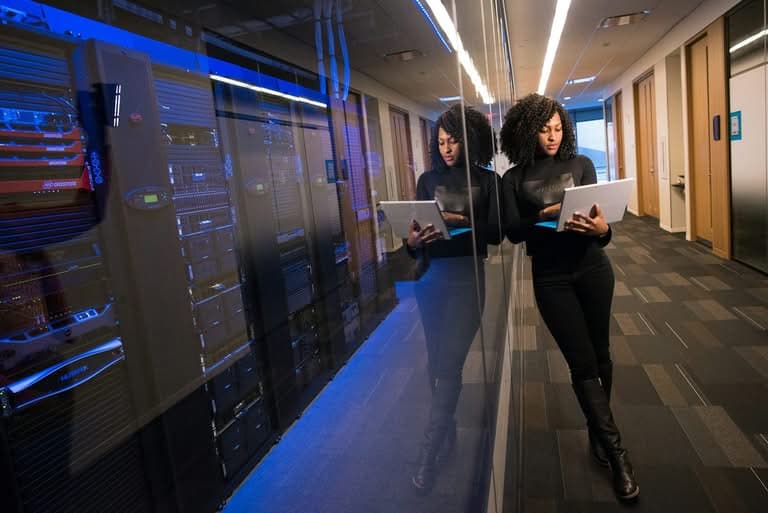 IT professional using a laptop in a server room