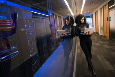 IT professional using a laptop in a server room