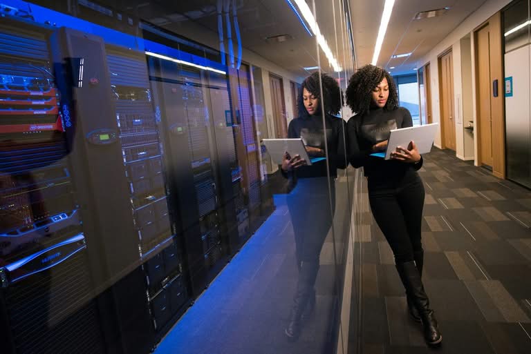 IT professional using a laptop in a server room